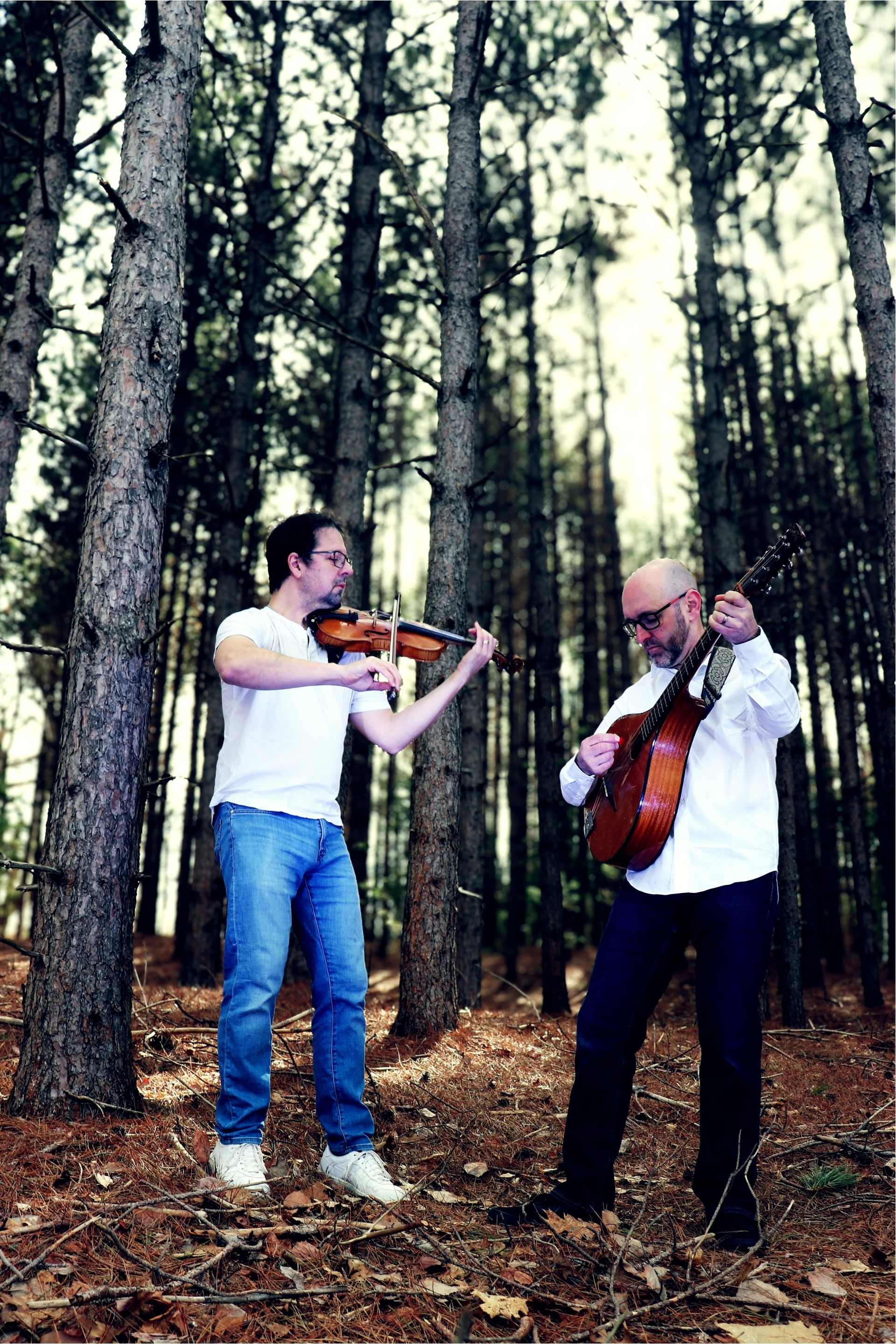 Jeremy and Andy playing fiddle and guitar among tall pines